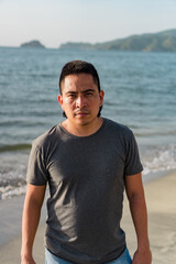 Serious young man looking at the camera on the beach, urban lifestyle concept