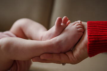 Close up on legs of unknown caucasian baby in hand of her mother parenthood growing up concept new life