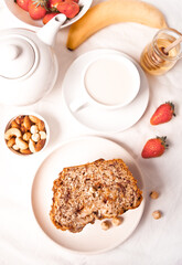 Sliced homemade banana bread with berries, cup of coffee or tea with milk. Healthy dessert concept. Top view.