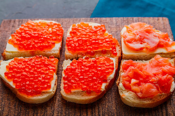 Bruschetta with red caviar on a handmade wooden board.