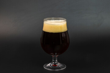 Close up view of poured dark beer into glass isolated on dark background.