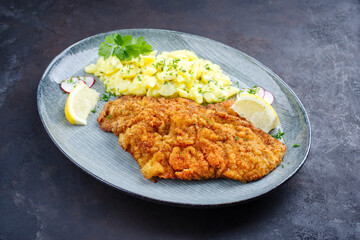 Traditionelles frittiertes Schnitzel mit Kartoffelsalat und Zitronenscheiben serviert als...