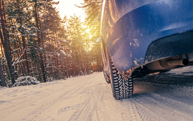 Car tires on a winter snow - covered forest road . Winter landscape with a blue car in the forest.
