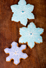 Homemade gingerbread cookies, festive Christmas and New Year sweets in the form of blue snowflakes background card, on a wooden board