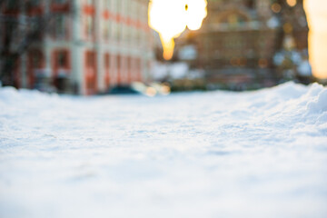 Winter in the city. Empty street. Snow cover. Sunset. Focus on snow. Close up view from the level of snow.