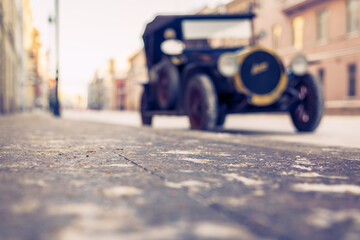 Winter in the city. The car is parked at the sidewalk. Antique car. Historical center of the city. Frosty snowy day.  Focus on the cobbled pavement. Close up view from the level of the pavement.