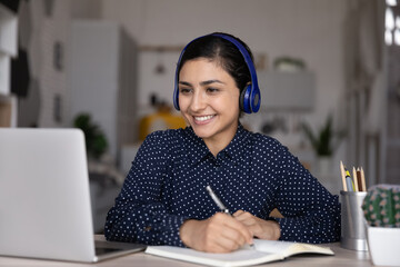 Happy ethnic Indian student girl watching learning media content, listening virtual webinar on...