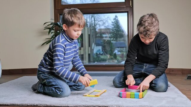 beautiful cute boys playing at home with creative wooden colorful constructor. Intellectual toys with wooden blocks, developmental board game, builiding structures. Educational leisure with children