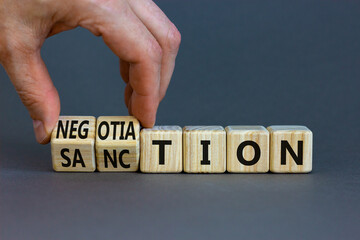 Sanction or negotiation symbol. Businessman turns cubes, changes the word sanction to negotiation. Beautiful grey table, grey background, copy space. Business, sanction or negotiation concept.