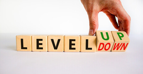 Level up or down symbol. Businessman turns cubes and changes concept words level down to level up. Beautiful white table, white background. Business and level up or down concept. Copy space.