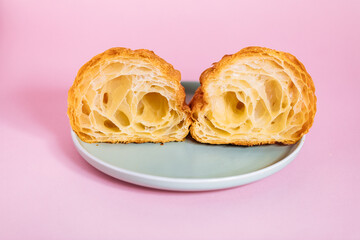 Croissant cut in two pieces isolated on purple background. Simple and elegant concept.