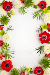 Flowers Frame composition. Arrangement of red anemone,white ranunculus, tropical flowers, green succulent and leaves on light background.