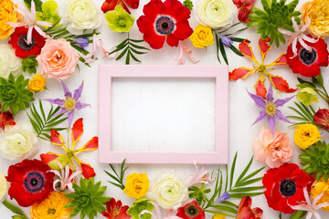 Frame and flowers composition. Arrangement of anemones, roses, ranunculus, tropical flowers, succulent and leaves on light background.