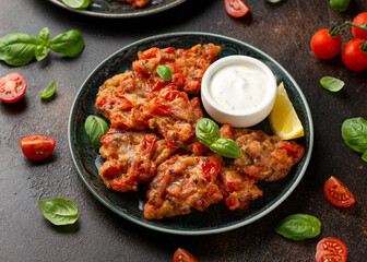 Greek tomato fritters, tomatokeftedes served with yogurt on plate.