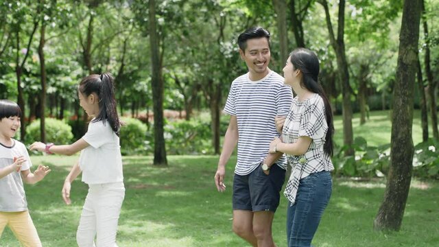 Asian family, parents and kids walking in green park