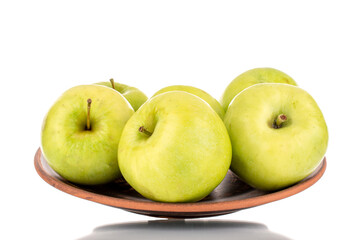Several sweet green apples on a clay dish, close-up, isolated on white.