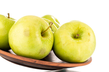 Several sweet green apples on a clay dish, close-up, isolated on white.