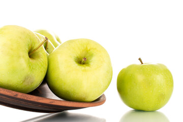 Several sweet green apples on a clay dish, close-up, isolated on white.