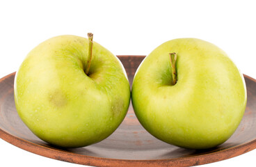 Two sweet green apples on a clay dish, close-up, isolated on white.