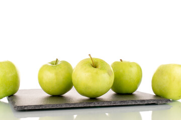 Several sweet green apples on a slate stone, close-up, isolated on white.