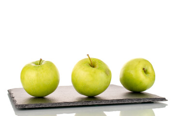 Three sweet green apples on a slate stone, close-up, isolated on white.