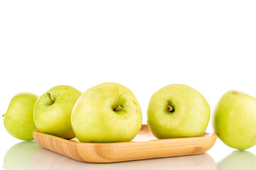 Several sweet green apples on a bamboo plate, close-up, isolated on white.