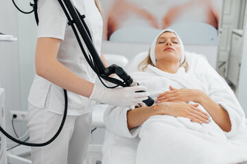 Obraz premium A young girl gets carbon peeling for the skin of her hands in a beauty salon. Laser pulses cleanse the skin. Hardware cosmetology. The process of photothermolysis, warming the skin.