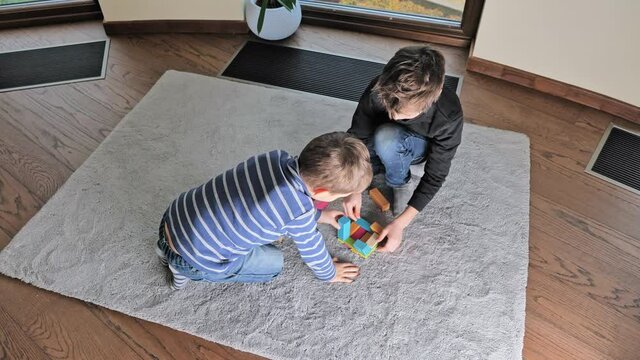 beautiful cute boys playing at home with creative wooden colorful constructor. Intellectual toys with wooden blocks, developmental board game, builiding structures. Educational leisure with children