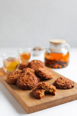 Tea time.

Healthy tea, adaptogenic drink, herbal tea with sea buckthorn berries. On a white table, a glass teapot and cups, cereal cookies with dried fruits on a wooden board. 