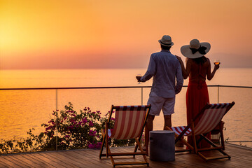 A loving couple on vacation time enjoys the beautiful summer sunset over the mediterranean sea with...