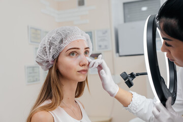 Cosmetic procedure for filling the nasolacrimal furrow and mesotherapy around the eyes for a young...