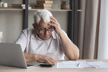 Confused stressed old mature retired 80s man in eyeglasses doing financial paperwork, feeling...