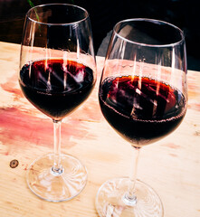 Two glasses of red wine, arranged on a table, during an outing in the countryside.