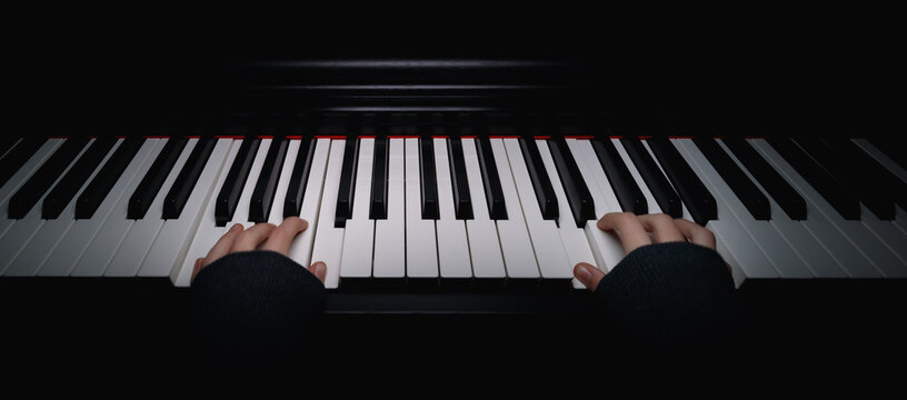 Point of view from a young girl playing the piano. Hands on the piano keyboard.