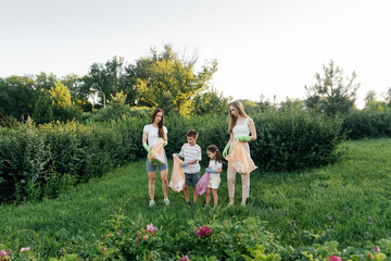 A group of adults and children together at sunset is engaged in garbage collection in the park....