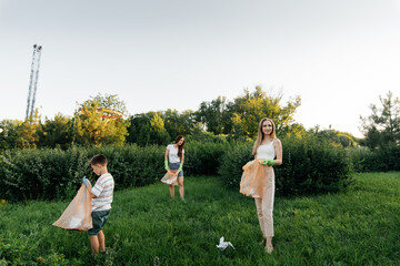 A group of adults and children together at sunset is engaged in garbage collection in the park....