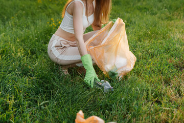 A girl in the park at sunset is engaged in garbage collection in the park. Environmental care,...