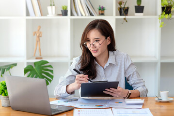 Pretty young Asian female student studying online on laptop computer.