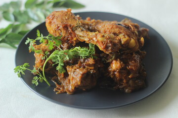 Kerala style dry chicken roast. Chicken cooked in a spicy gravy of onion tomatoes and spices served with chicken leg pieces on top