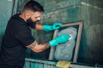 Male worker cleaning screen frame with a cloth in a printing workshop