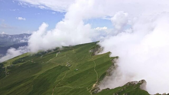 Drone footage of 
hiking trails in dolomites on the edge of rocks covered in clouds. Scenic cloud covered landscape. 