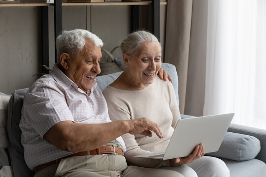 Surprised happy old senior retired family couple looking at laptop screen, enjoying web surfing information, watching funny movie online, learning using software applications, reading good news.