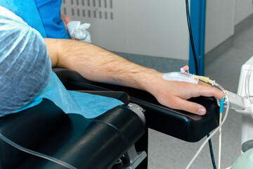 Anesthesia catheter in human hand during surgery. Selective focus. Intravenous drip catheter in the patient's hand on the operating table. General anesthesia during surgery.