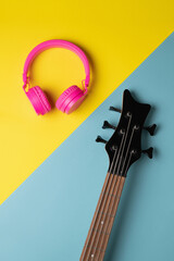 headstock of a guitar and headphones placed each on one side of the diagonal division of the...