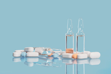 Medical background. many capsule tablets or pills on blue table. Glass vials. Vaccine. Close up. Healthcare pharmacy and medicine concept with copy space Painkillers or prescription drugs consumption - obrazy, fototapety, plakaty