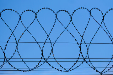 Spulen von Stacheldrahtzaun hinter blauem Himmel