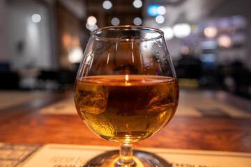 Glass of Burban / Whisky with ice cubes in it in front of blurred hotel bar background