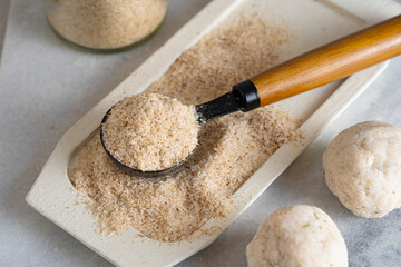 Psyllium husk on spoon soluble fiber supplement and raw bread or buns balls made of it before cooking. Superfood for healthy, lowers cholesterol, eases constipation. Keto, paleo low carb diet