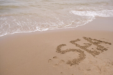 The word sea on the wet sand.  Foamy waves. Copy space. 