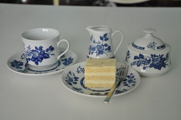Fine porcelain set for coffee-tea and cheesecake on plate. Old school style tea at five afternoon service cake sweet traditional table, cheesecake sugar pot blue china cup